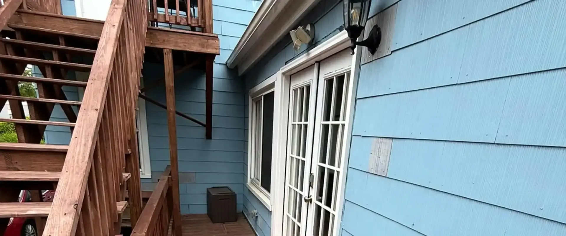 Blue-painted exterior siding beside a weathered wood staircase on a multi-level home
