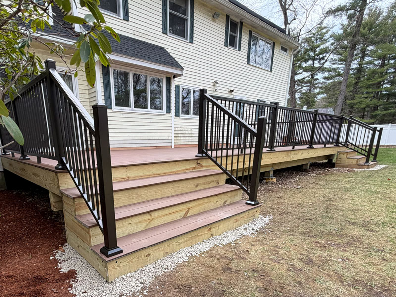 Composite deck replacement with wood framing accents and black aluminum railings with stairs