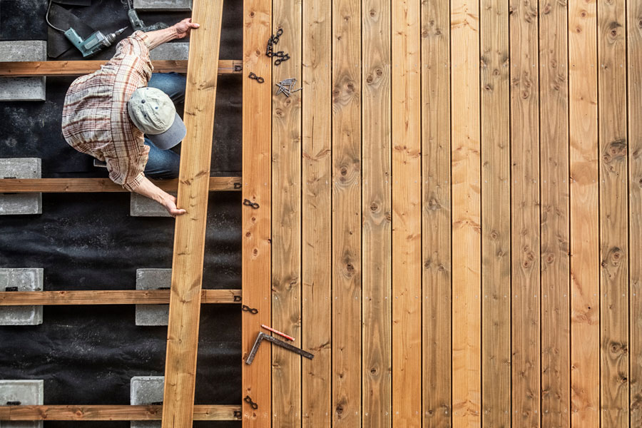 Deck framing and wood decking boards being installed during construction