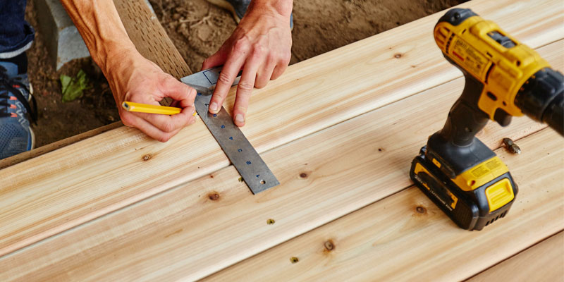 Measuring and cutting wood deck boards during deck construction
