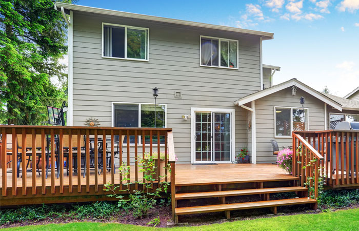 Backyard wood deck with stairs and railing attached to a home