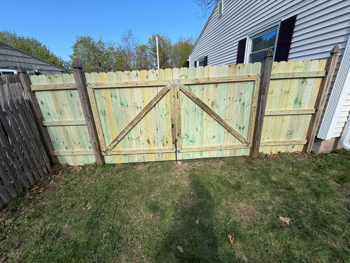 New wood fence installation with 10 ft double gate using pressure-treated dog-ear pickets