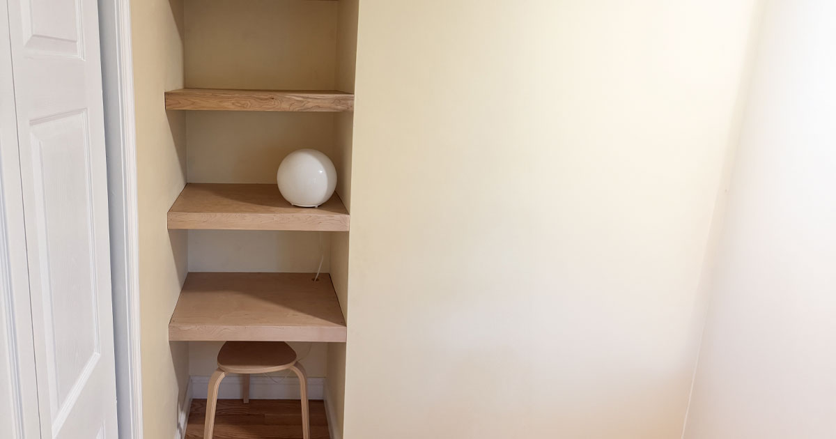 Custom built-in wood shelving installed inside a recessed wall niche