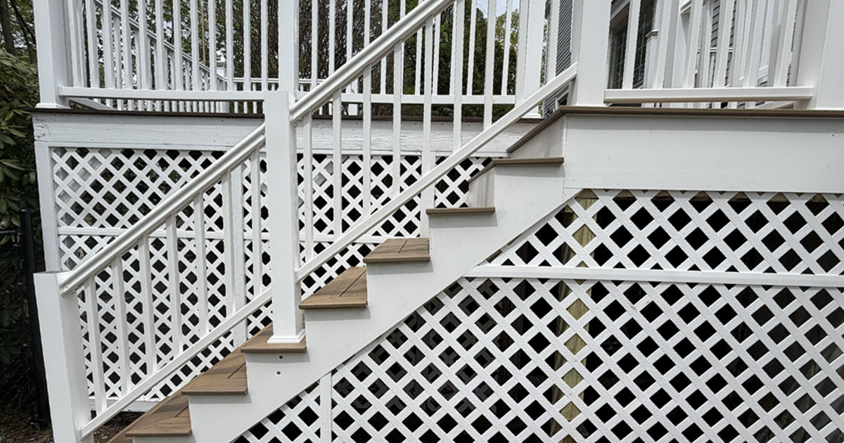 Completed composite deck stair replacement with white PVC railings, composite stair treads, and lattice skirting installed by White Pine Builds.