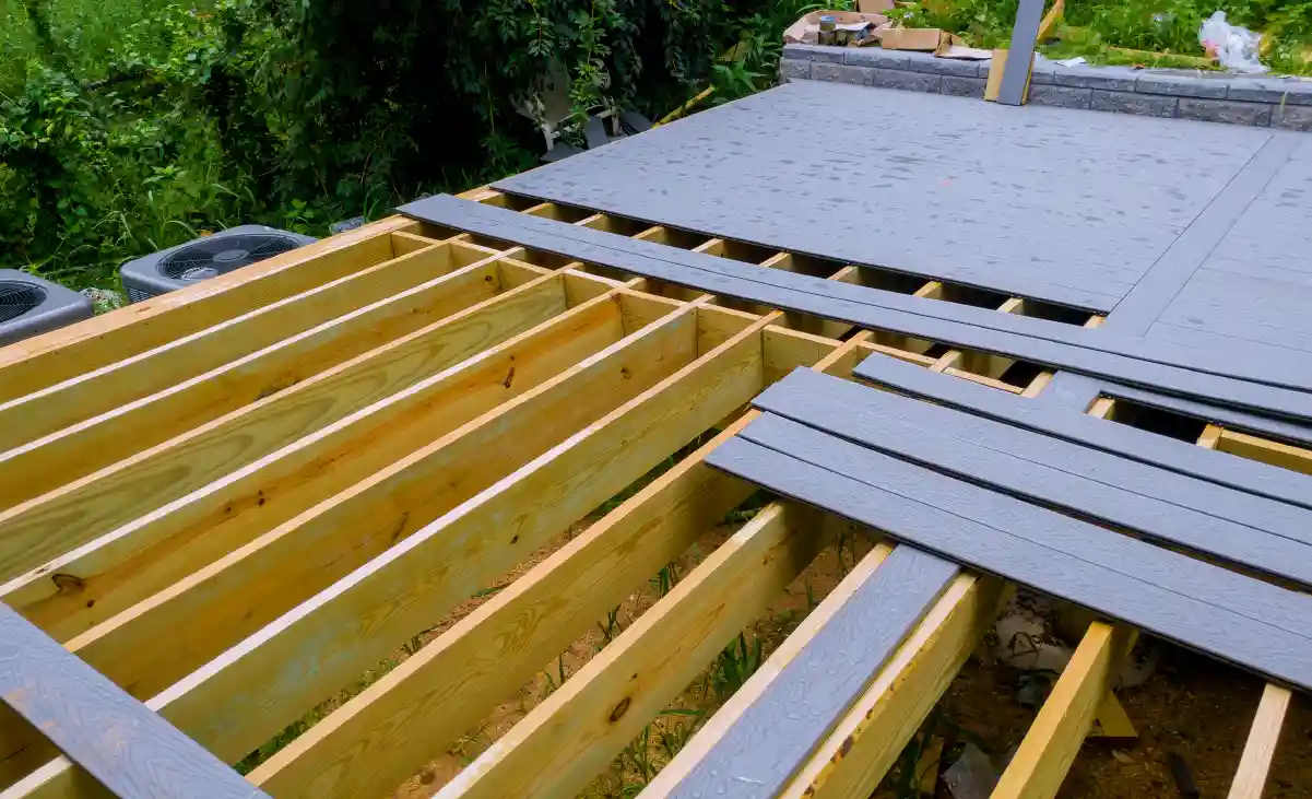Deck replacement in progress with new framing and composite decking being installed on a rebuilt backyard deck.