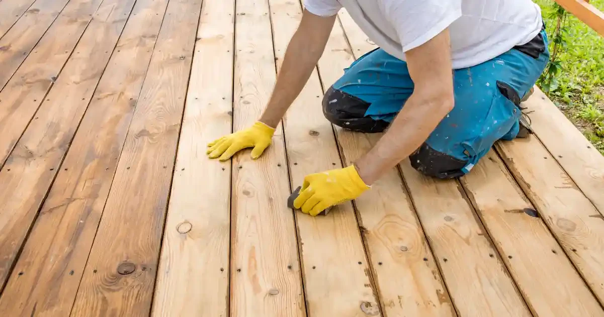 Contractor aligning and installing wood decking boards during custom deck construction on a residential outdoor deck.