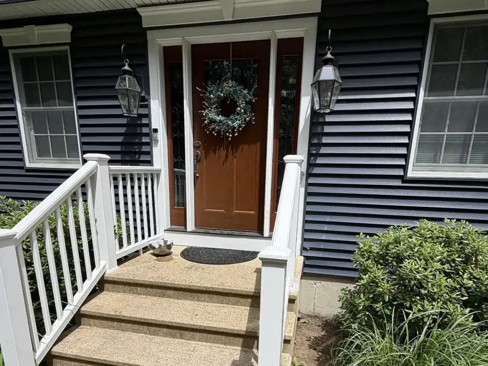 Front entry of a Hartford County home with wood door, white railings, and finished steps.