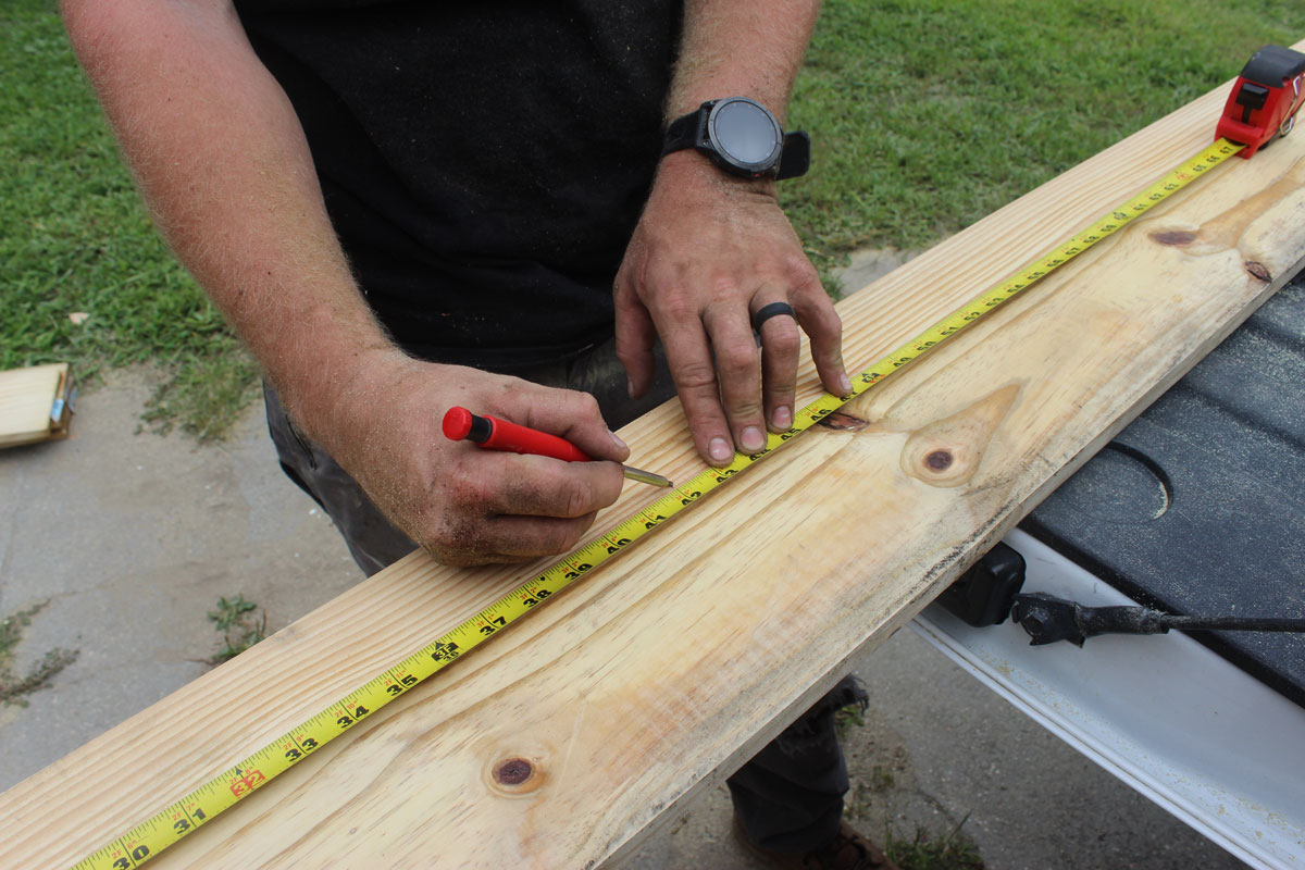 Contractor measuring and marking lumber for custom deck construction by White Pine Builds.