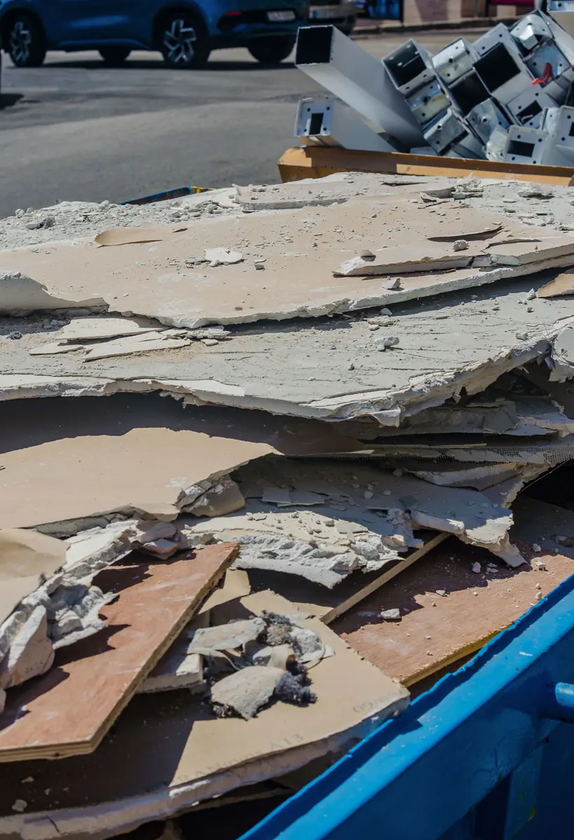 Demolition debris and broken drywall loaded into a dumpster for removal and disposal