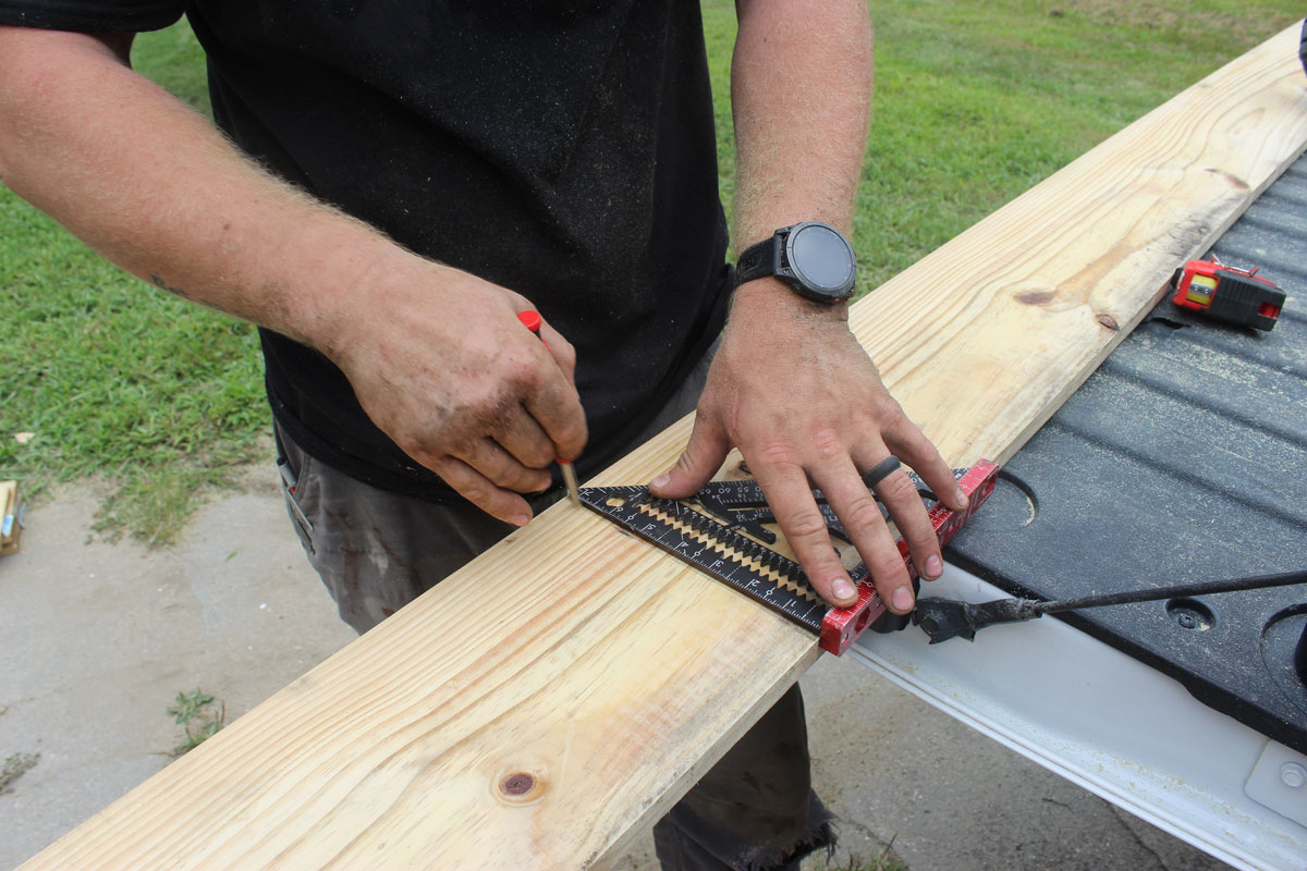 White Pine Builds contractor marking lumber with a framing square for a residential construction project.
