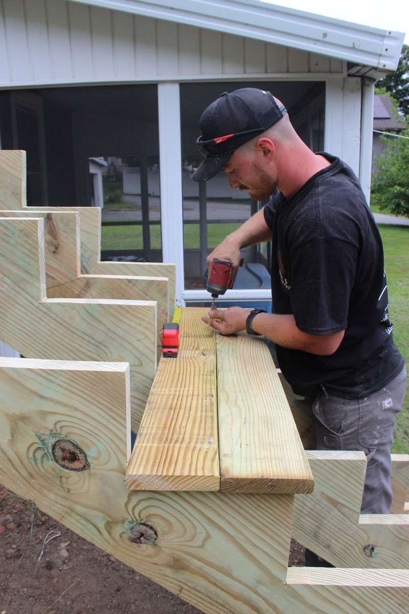 White Pine Builds contractor measuring and fastening lumber during a custom outdoor construction project.
