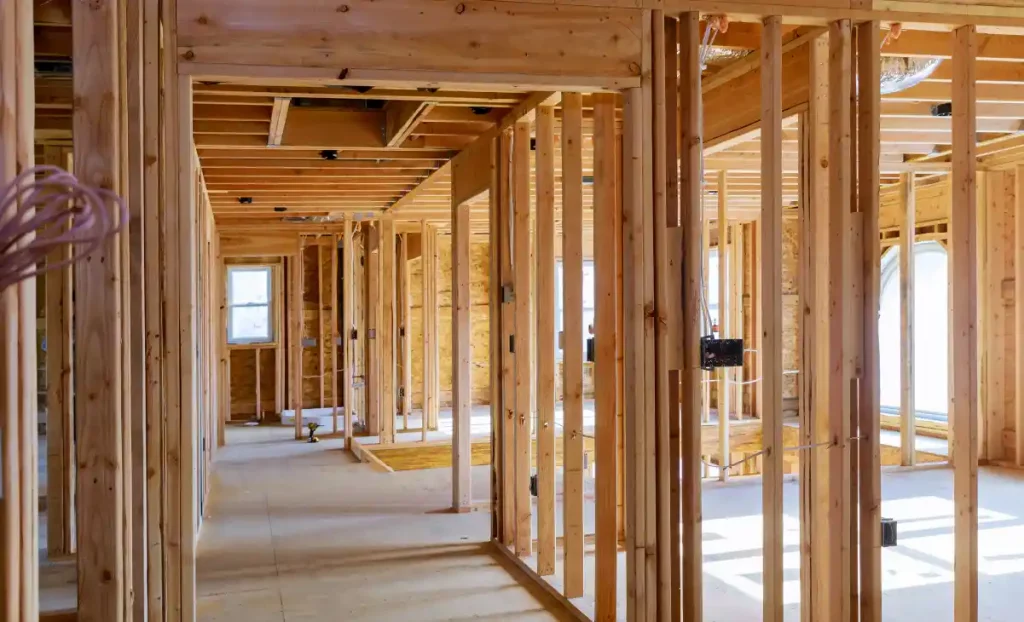Interior home framing during a whole-home remodel showing new wall studs, open floor plan, and structural construction before drywall installation.