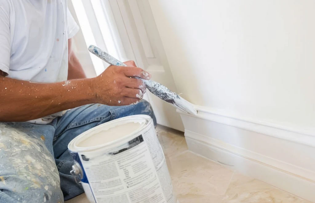 Handyman painting interior trim and baseboards as part of residential home maintenance and finish work