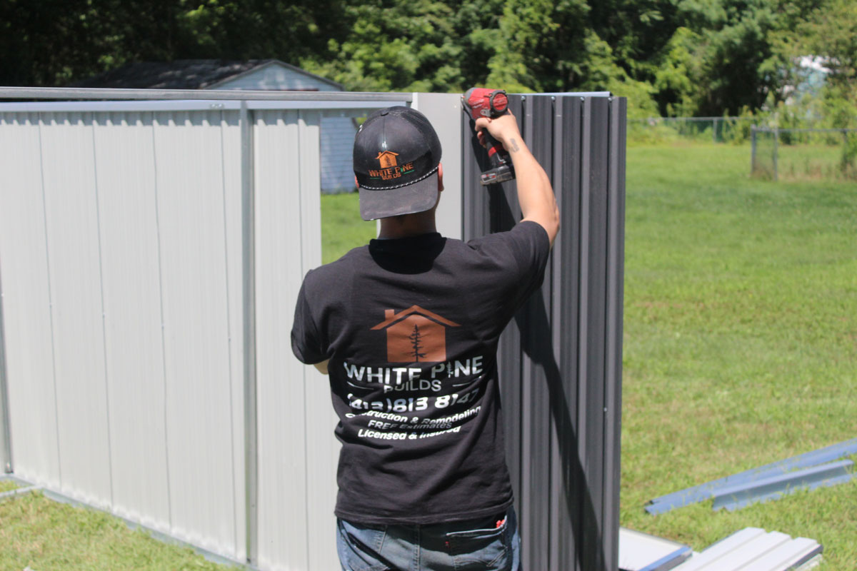 White Pine Builds contractor assembling a custom metal shed in a residential backyard.
