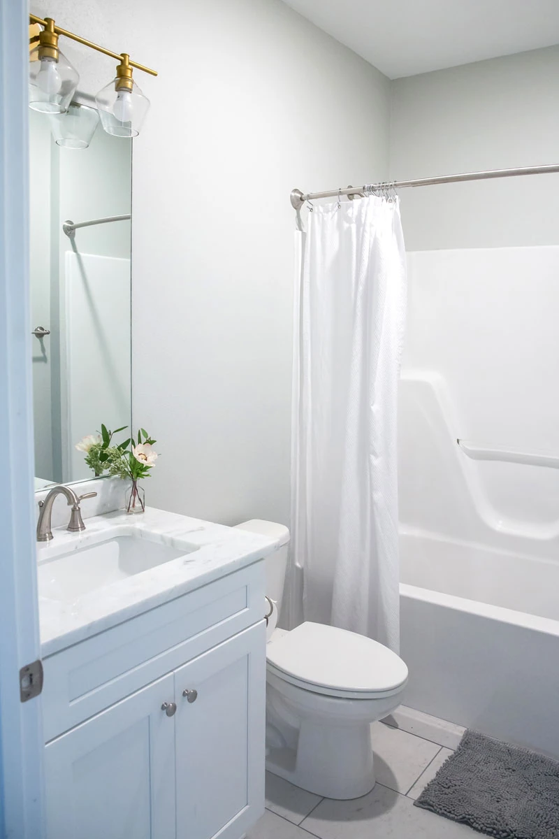 Bathroom remodeling Worcester MA featuring a custom white bathroom vanity, bathtub and shower installation, tile flooring, and modern fixtures.
