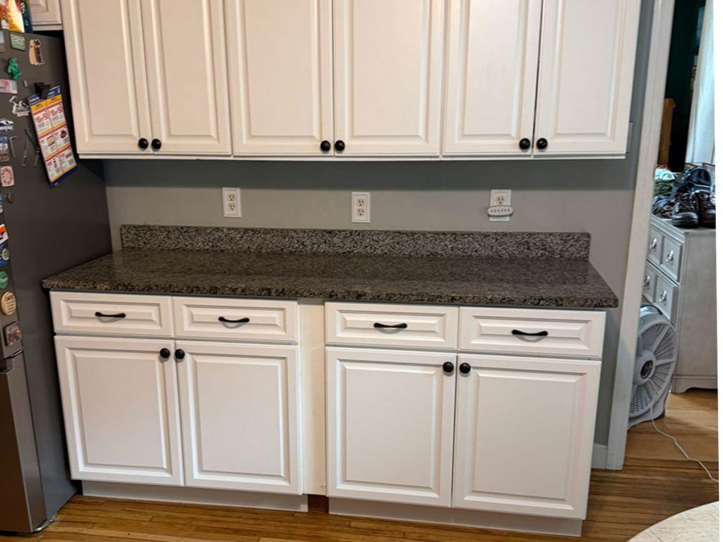 Kitchen cabinet remodel with painted white cabinets, granite countertops, updated hardware, and a refreshed workspace.