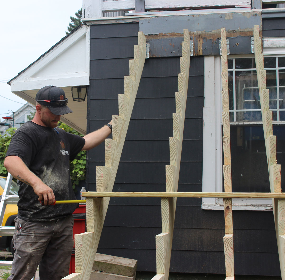 White Pine Builds contractor measuring custom stair framing during a residential remodeling project.